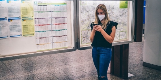 Frau mit Handy in der Hand vor einem Liniennetzplan