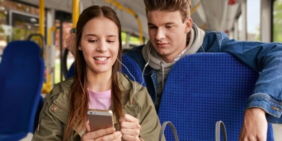 Junge und Mädchen mit Smartphone im Bus