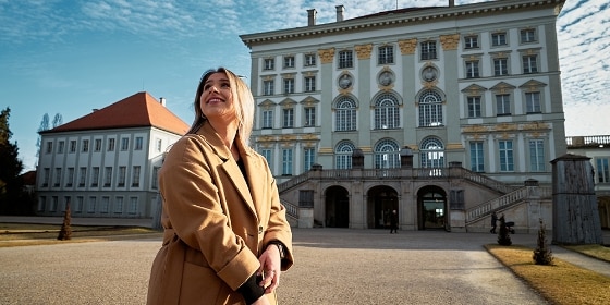 Eine Frau steht vor Schloss Nymphenburg