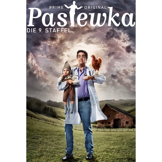 Pastewka steht mit Kind und Huhn auf dem Arm auf einer Weide in den Bergen. 