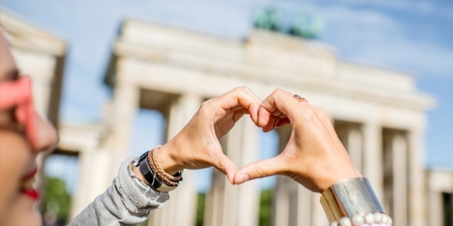 Schmuckbild - Frau vor Brandenburger Tor in Berlin formt Herz mit ihren Händen.