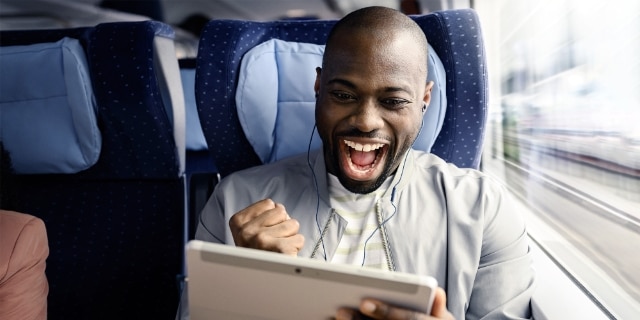 Person mit Tablet und Kopfhörer im Zug