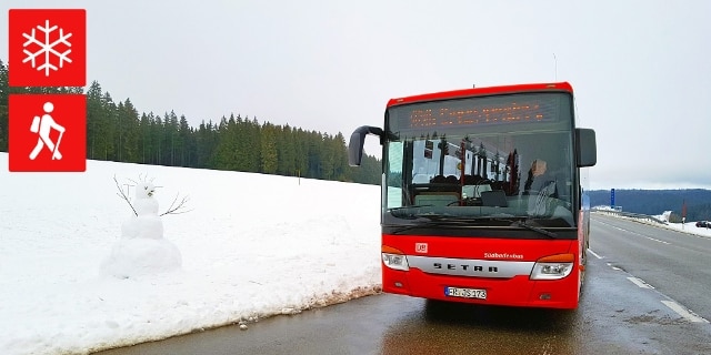 Panoramabus im Winter neben Schneemann