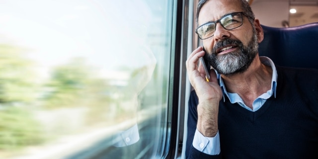 Mann telefoniert und schaut aus dem Zugfenster