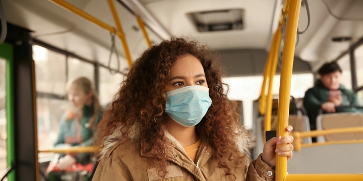 Afroamerikanerin mit Einwegmaske im Bus. Virenschutz