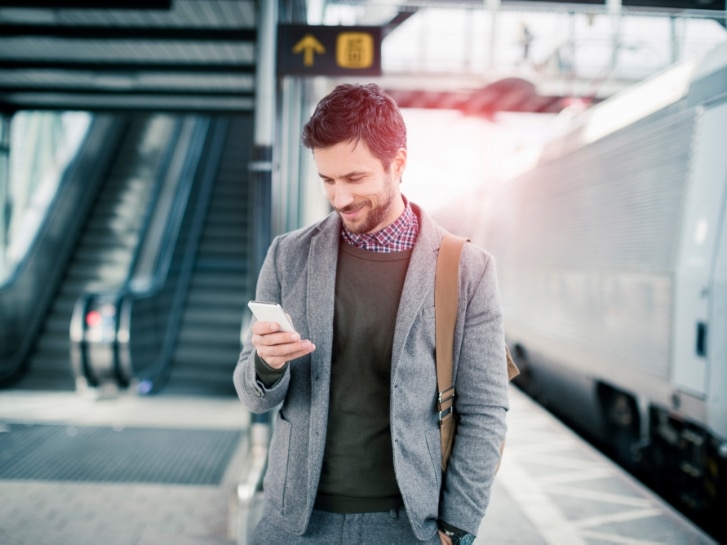 Businessman using mobile phone at train station