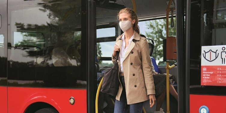Frau mit Maske steigt aus Bus