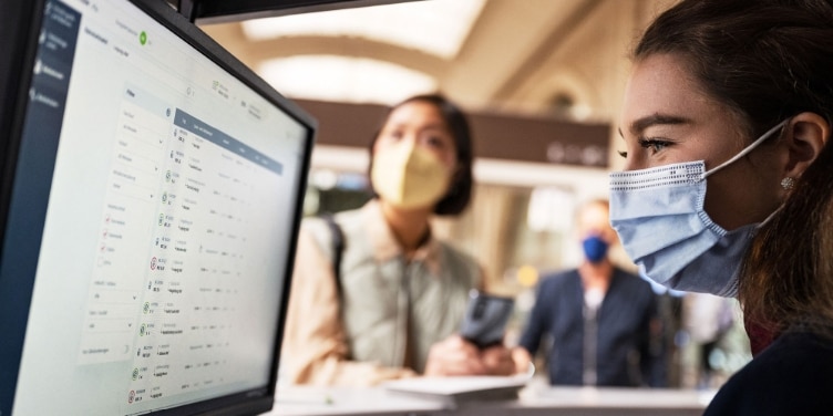 2 Frauen mit Masken vor Bildschirm