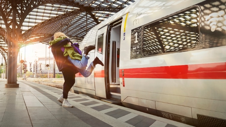 Frau springt mit Freude in die Arme von einem Mann am Bahnsteig