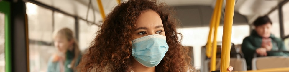 Afroamerikanerin mit Einwegmaske im Bus. Virenschutz
